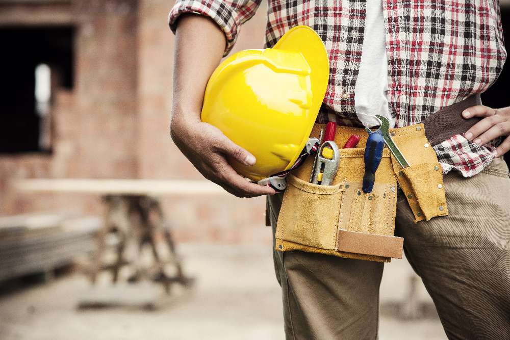 a construction worker holding his helmet on his hip
