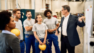 temp agencies male employee in group meeting at factory plant